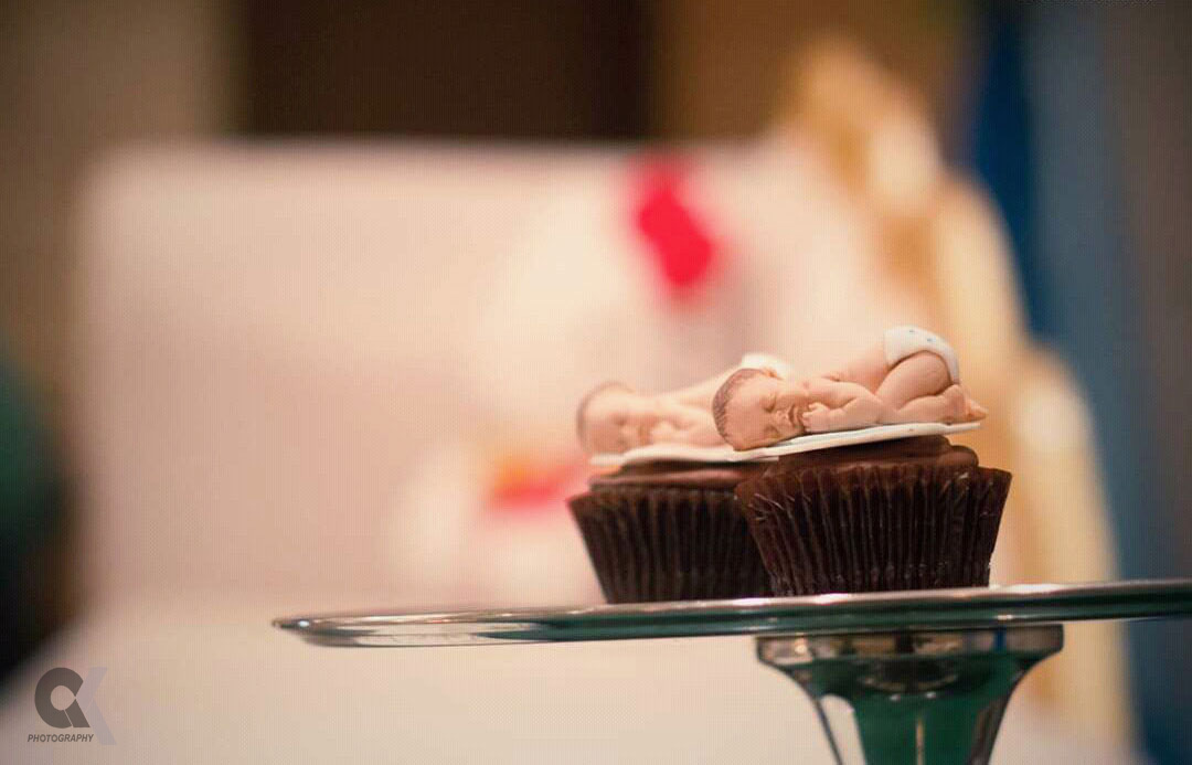 Baby-shaped fondant figures atop chocolate cupcakes at a celebration.